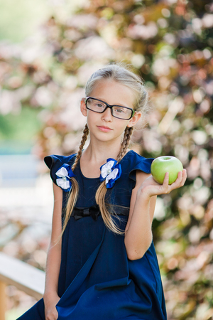 Adorable little school girl with green apple outdoor. Back to school conceptの写真素材