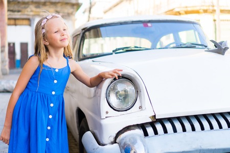 Adorable little girl in popular area in Old Havana, Cuba. Portrait of kid background vintage classic american carの写真素材