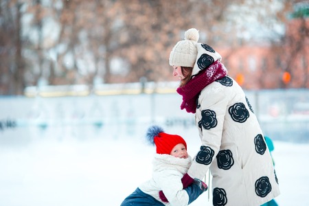 Little adorable girl with mother skating on ice-rink with motherの写真素材