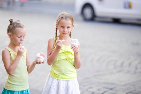Happy little girls eating ice-creamin open-air cafe. People, children, friends and friendship conceptの写真素材