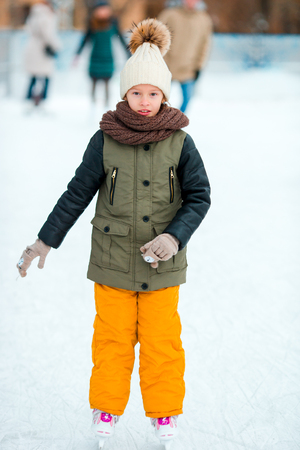 Adorable little girl going skate in winter snow day outdoorsの写真素材
