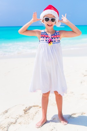 Adorable little girl in Santa hat during Christmas beach vacationの写真素材
