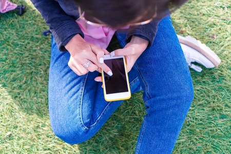 Closeup of female hands is holding cellphone outdoors on the street. Woman using mobile smartphone.