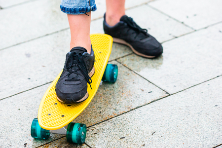 Hipster girls with skateboard outdoors in the rain. Closeup skatebord. Active sporty woman having fun in skate park.の写真素材