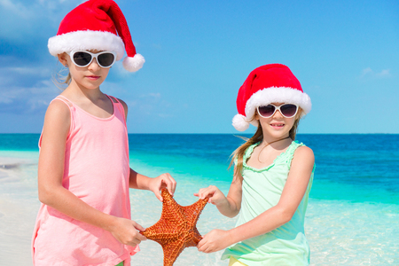 Adorable little girls on Christmas holidays on the beachの写真素材
