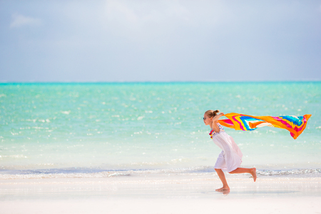 Little girl have fun on the beach. Kid enjoy beach vacation with pareoの写真素材