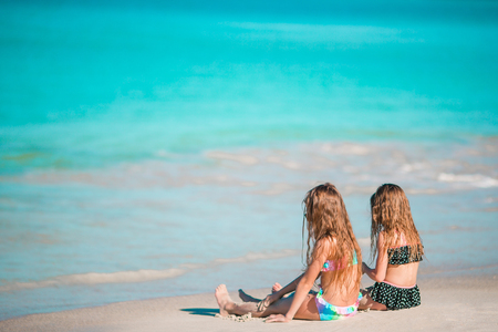 Adorable little girls relaxing on the beachの写真素材