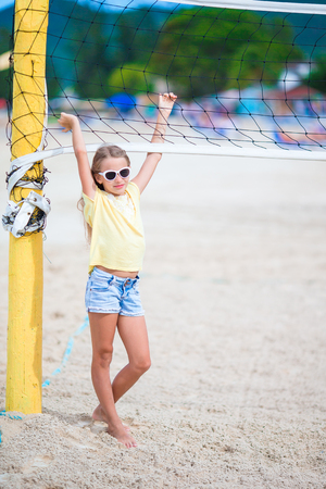 Little adorable girl playing beach volleyball with ball. Sporty family enjoy beach game outdoorsの写真素材