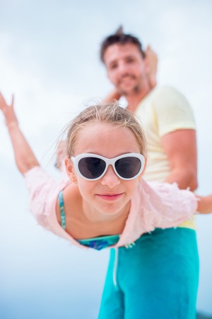 Little girl outdoors during summer vacation have fun with father. Portrait of a kid upside down on a sky backgroundの写真素材