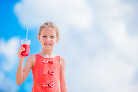 Cute little girl drinking cocktail on tropical beachの写真素材