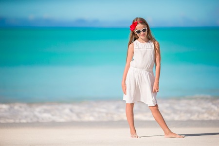 Beautiful little girl in white dress at beach having fun.の写真素材