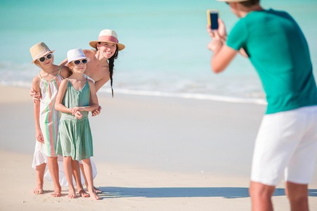 Man taking a photo of his family on the beach. Family beach vacationの写真素材
