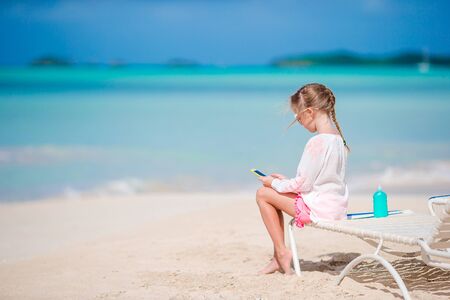 Little girl playing with by her smart phone sitting on the sunbedの写真素材