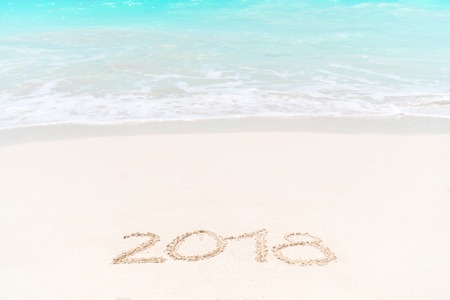 2018 handwritten on sandy beach with soft ocean wave on background