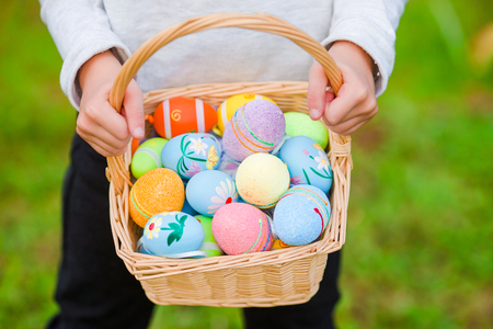 Closeup basket full of colorful Easter eggs in kids handsの写真素材