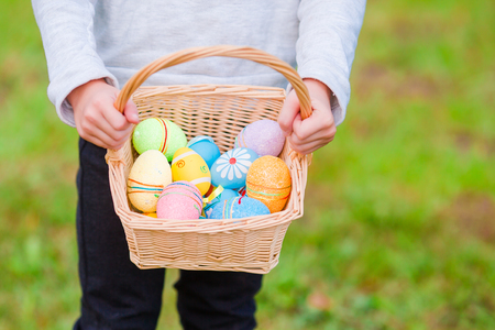 Closeup basket with colorful Easter eggs in kids handsの写真素材
