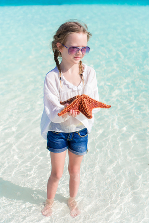 Adorable little girl with starfish on the beachの写真素材