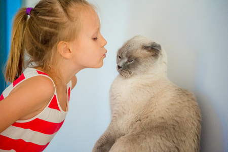 Cute little girl kissing her pet cat at home. Love between kid and petの写真素材