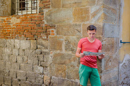 Young man with a city map at european city. Caucasian tourist looking at the map of European cityの写真素材