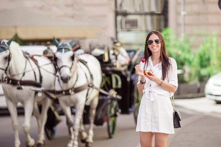Tourist girl enjoying vacation in Vienna and looking at the beautiful horses in the carriageの写真素材