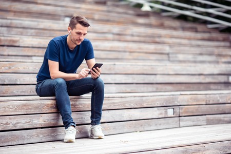 Man is reading text message on mobile phone while walking in the park