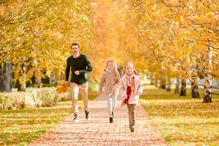 Family of dad and kids on beautiful autumn day in the parkの写真素材