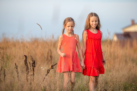 Beautiful little blonde girls, has happy fun cheerful smiling face, red dressの写真素材
