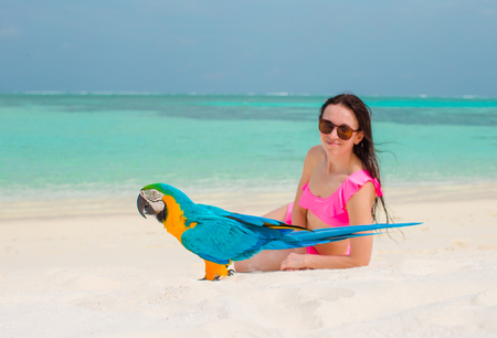 Adorable girl at beach with colorful parrot