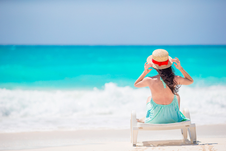 Young woman on a tropical beach with hat on beach bedaの写真素材
