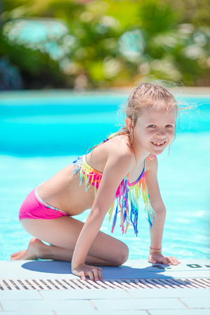 Little active adorable girl in outdoor swimming pool ready to swimの写真素材