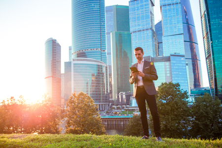 Businessman looking on copy space while standing against glass skyscraperの写真素材