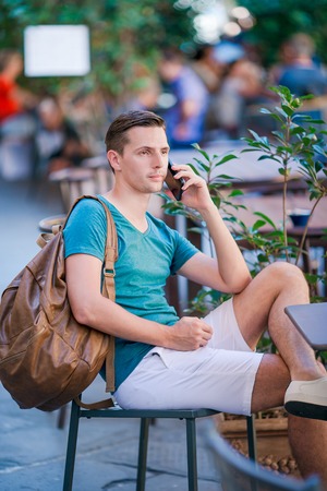 Caucasian boy is holding cellphone outdoors on the street. Man using mobile smartphone.の写真素材