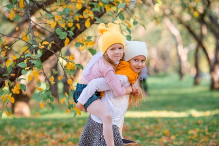 Little adorable girls at warm day in autumn park outdoorsの写真素材