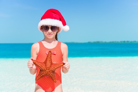 Happy little girl in Santa hat during Christmas beach vacation have a lot of funの写真素材