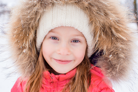 Portrait of little adorable girl in snow sunny winter dayの写真素材