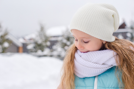 Portrait of little adorable girl in snow sunny winter dayの写真素材