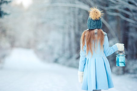 Adorable little girl with flashlight on Christmas at winter forest outdoorsの写真素材