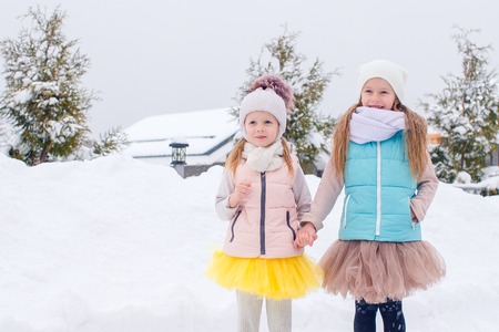 Adorable girls skating on ice rink outdoors in winter snow dayの写真素材