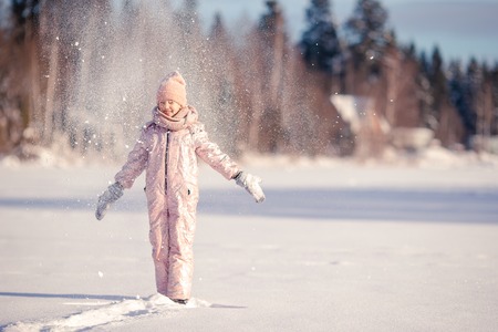 Adorable little happy girl sledding in winter snowy day.の写真素材