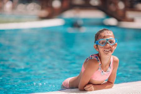 Beautiful little girl having fun near an outdoor poolの写真素材