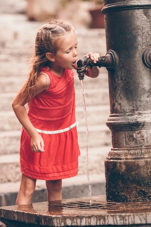 Little girl having fun with drinking water at street fountain in Rome, Italy