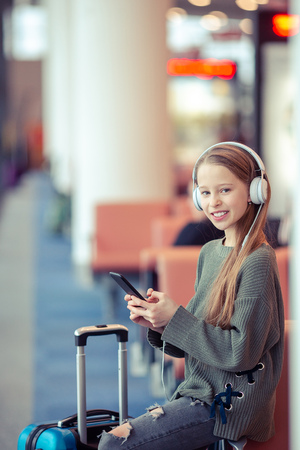 Adorable little girl at airport in big international airport near windowの写真素材