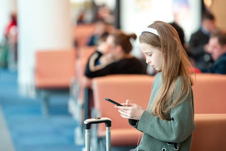 Adorable little girl at airport in big international airport near windowの写真素材