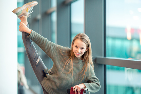 Adorable little girl at airport in big international airport near windowの写真素材