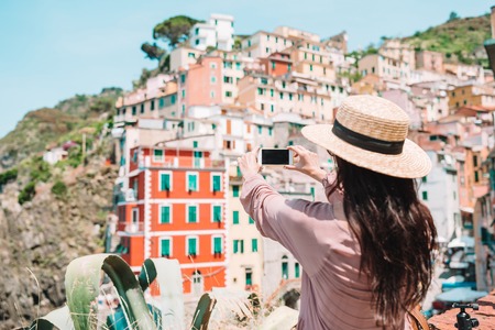 Young woman taking selfie background beautiful old italian village, Cinque Terre, Liguriaの写真素材