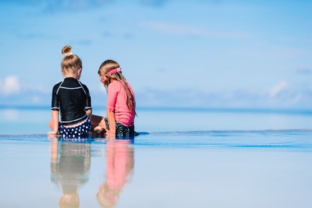 Adorable little girls playing in outdoor swimming poolの写真素材