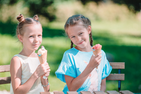 Little girls eating ice-cream outdoors at summer in outdoor cafeの写真素材
