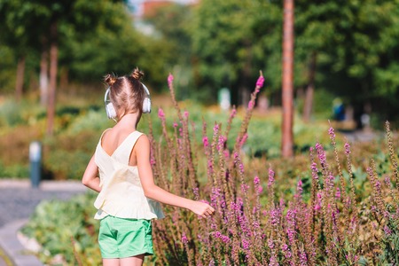 Little adorable girl listening music in the parkの写真素材