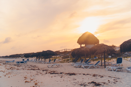 Idyllic tropical beach with white sand, turquoise ocean water and sunbeds and umbrellas at sunsetの写真素材