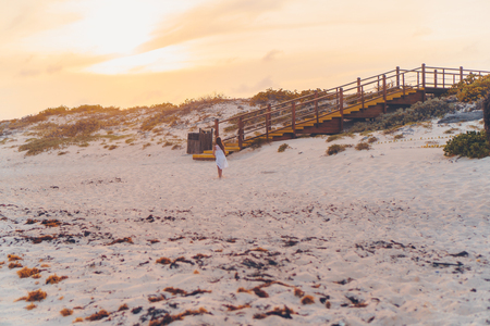 Idyllic tropical beach with white sand, turquoise ocean water and sunbeds and umbrellas at sunsetの写真素材